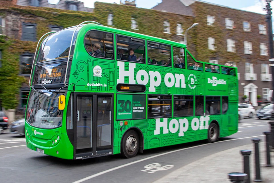 Green bus travelling in front of old buildings