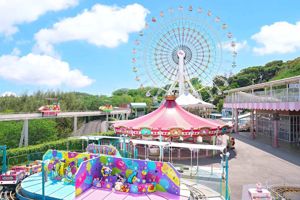 An amusement park with a colorful carousel and a large Ferris wheel under a bright blue sky surrounded by trees.