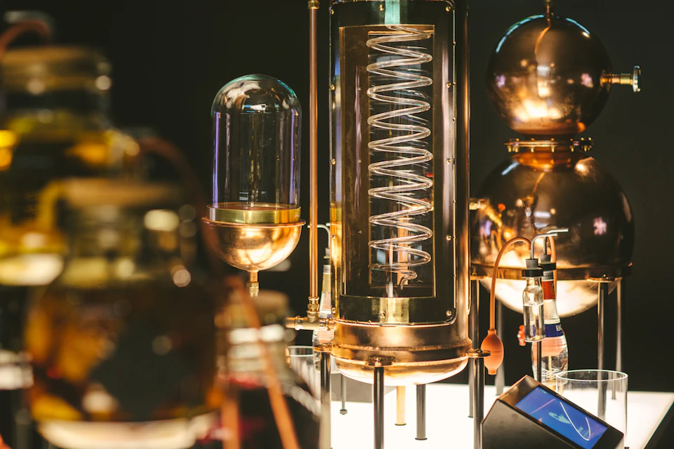 Close-up of vintage scientific laboratory equipment, featuring glass domes, copper coils, and metal structures with a dark background.