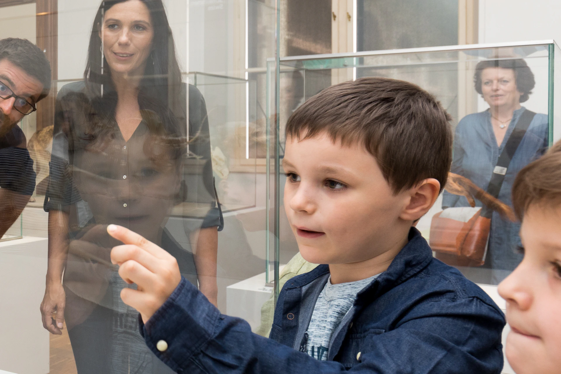 Two boys and three adults observe a taxidermy cheetah in a museum exhibit.