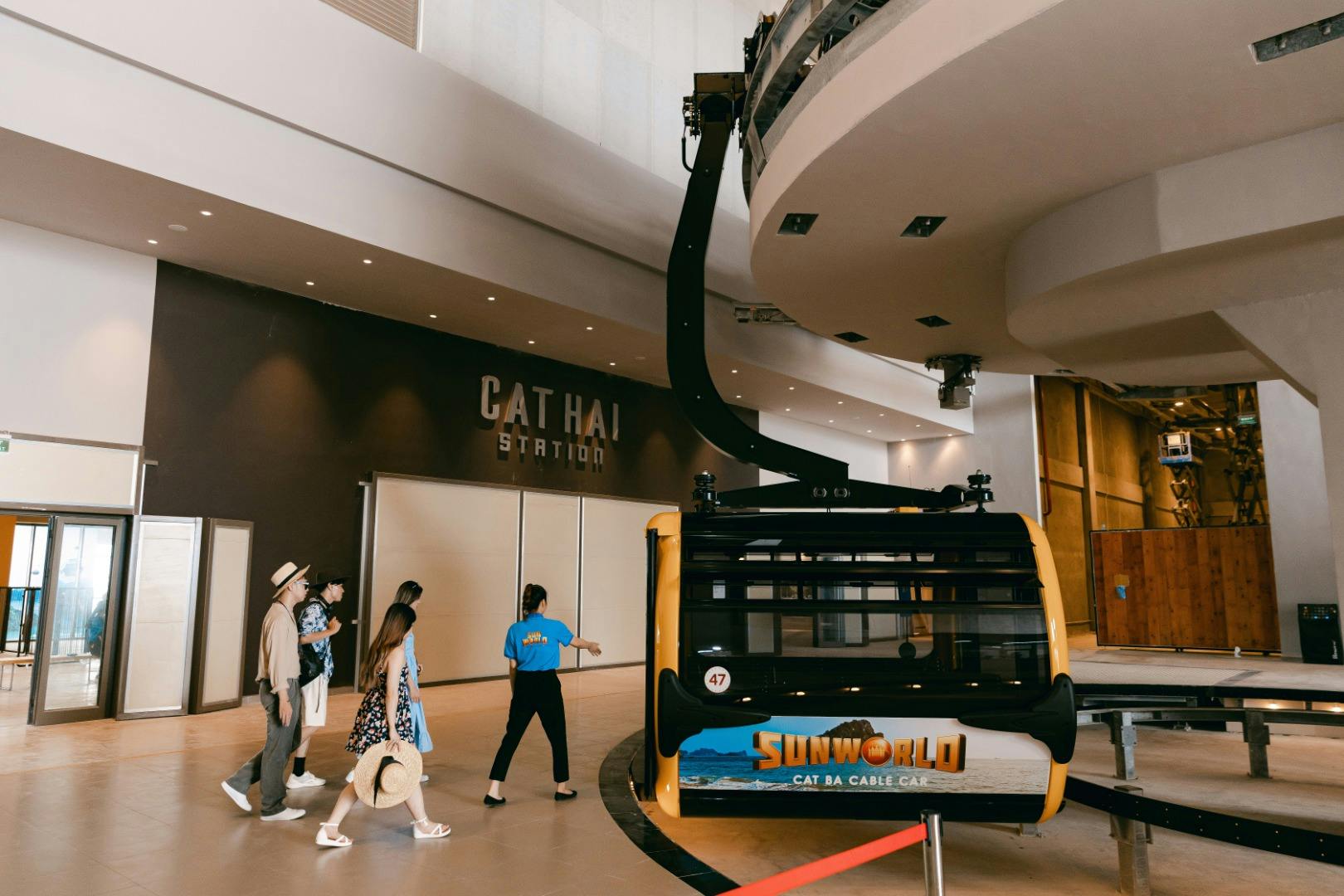 People walking near a cable car labeled 'Sun World Cat Ba Cable Car' at Cat Hai Station indoors.