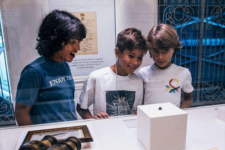 两个孩子在博物馆的白色陈列柜里观察一件小文物。 两人都穿着白衬衫。