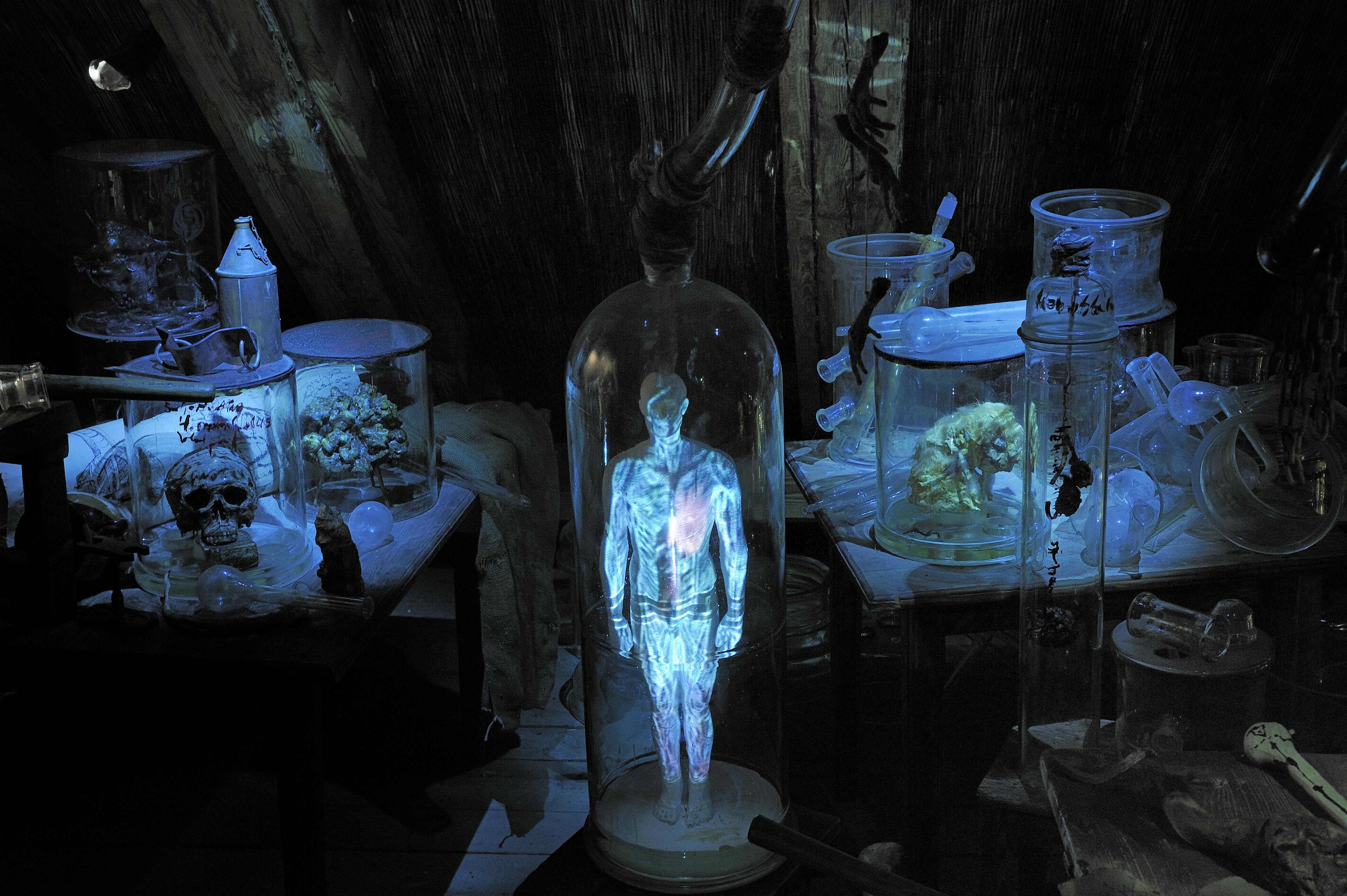 玻璃圆柱体中的发光全息人物，在昏暗的房间里被各种科学设备和容器包围。