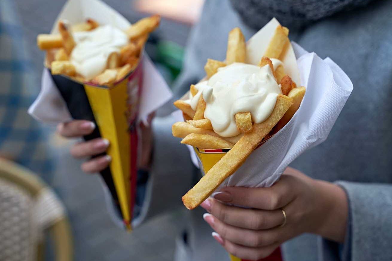两个人拿着配有蛋黄酱的薯条。