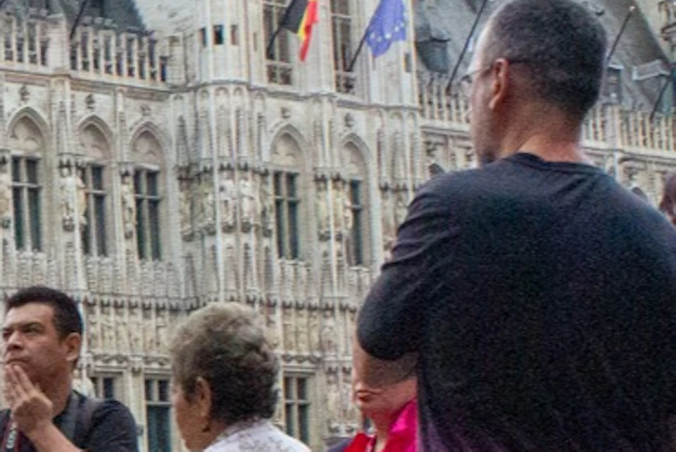 A group of people gathered on a cobblestone square in front of an ornate historic building with spires and detailed architecture.