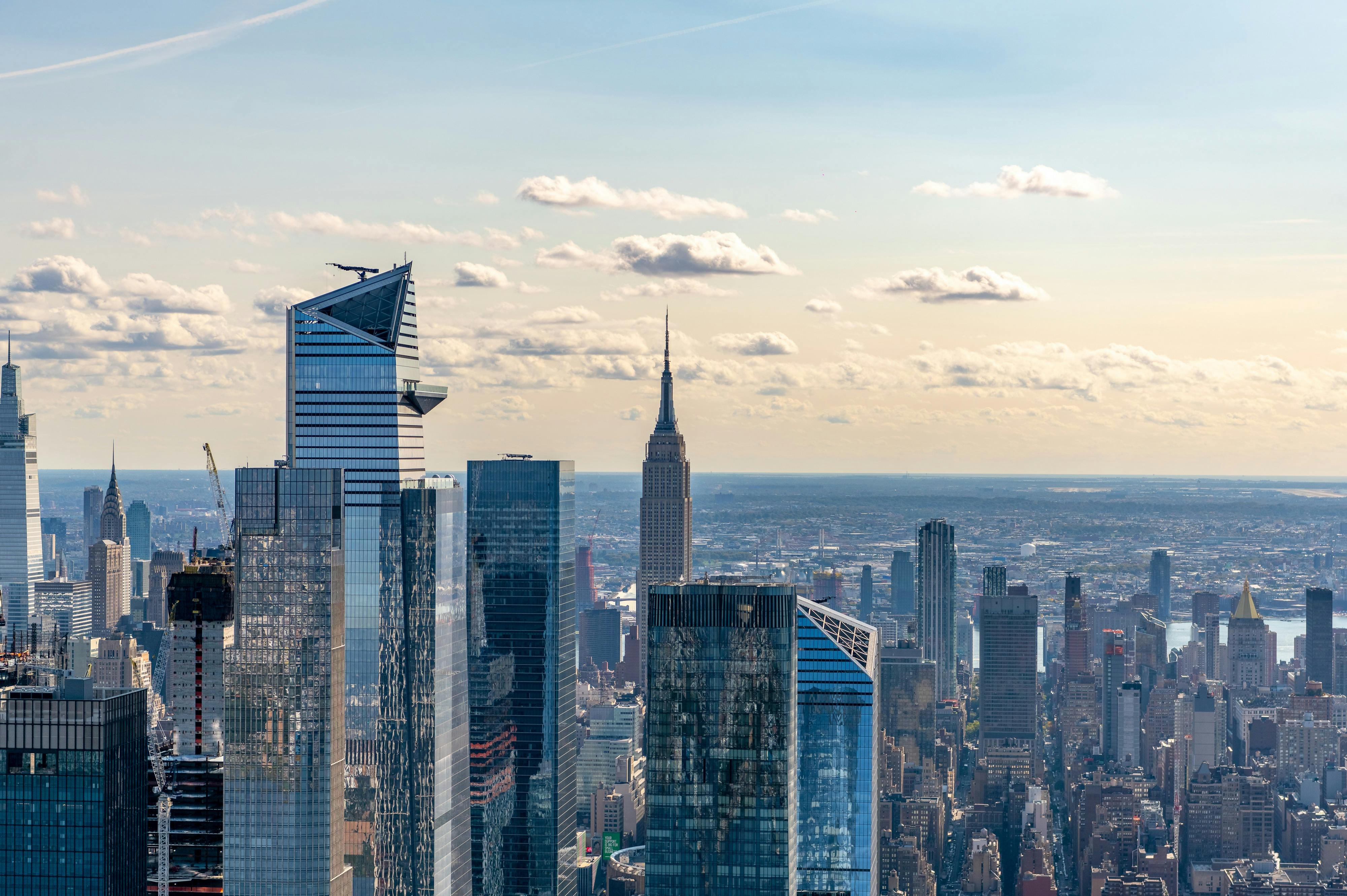 部分的に曇った空の下で、エンパイア・ステート・ビルディングを含むニューヨーク・シティの高層ビル群を眺めることができます。