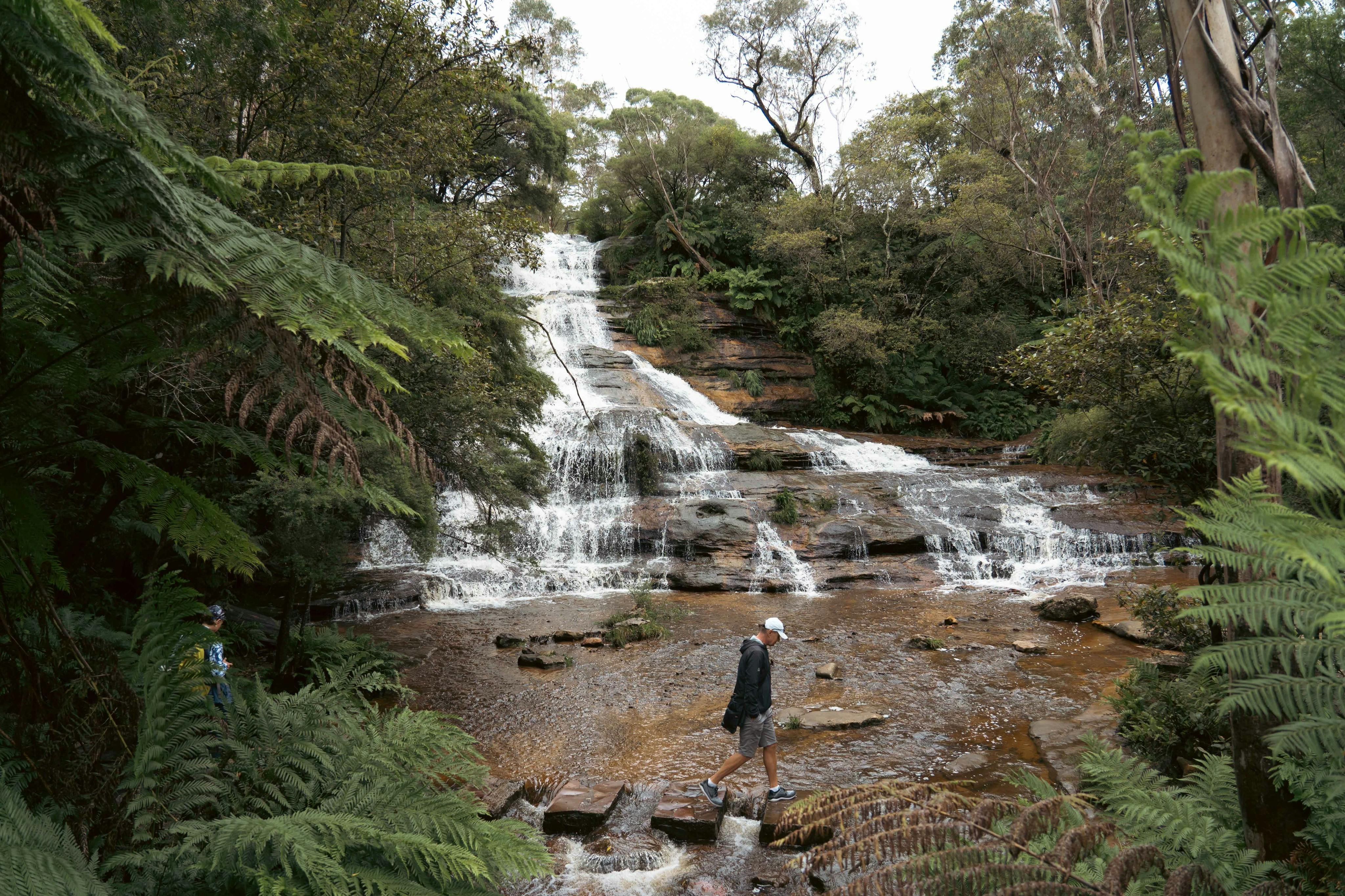 Spaziergang auf Trittsteinen am Fuße der beeindruckenden Katoomba Cascades Waterfalls