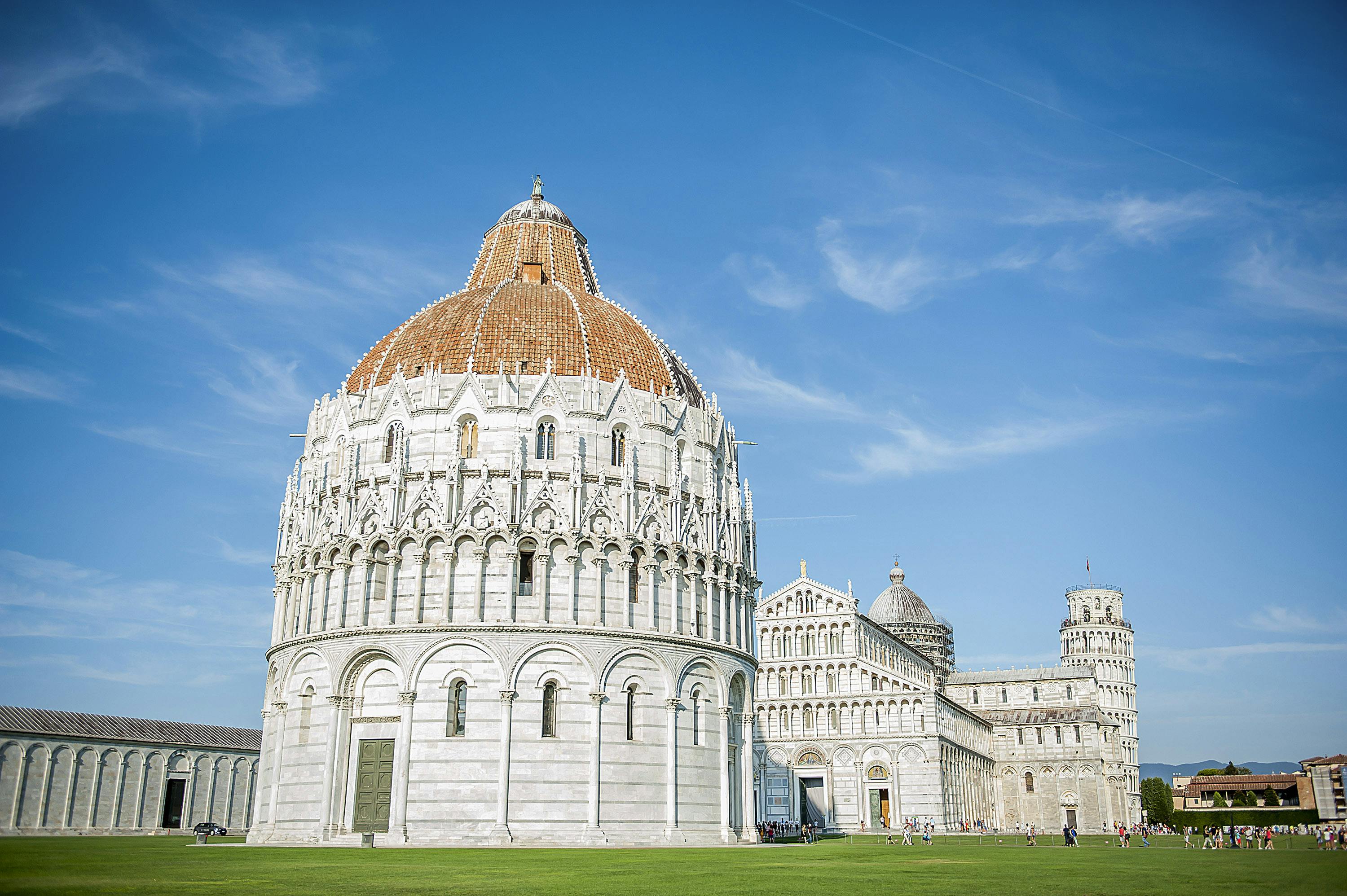 白色大理石洗礼堂，屋顶为圆顶，是晴朗蓝天下的大教堂建筑群的一部分。