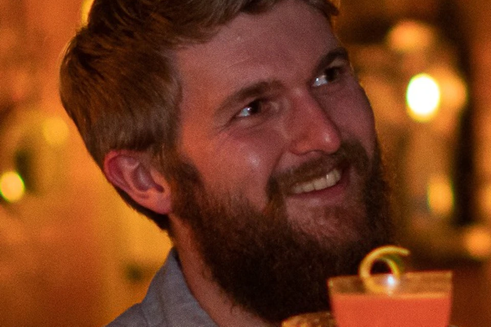 A group of people toasting with drinks in a warmly lit bar, smiling and socializing.