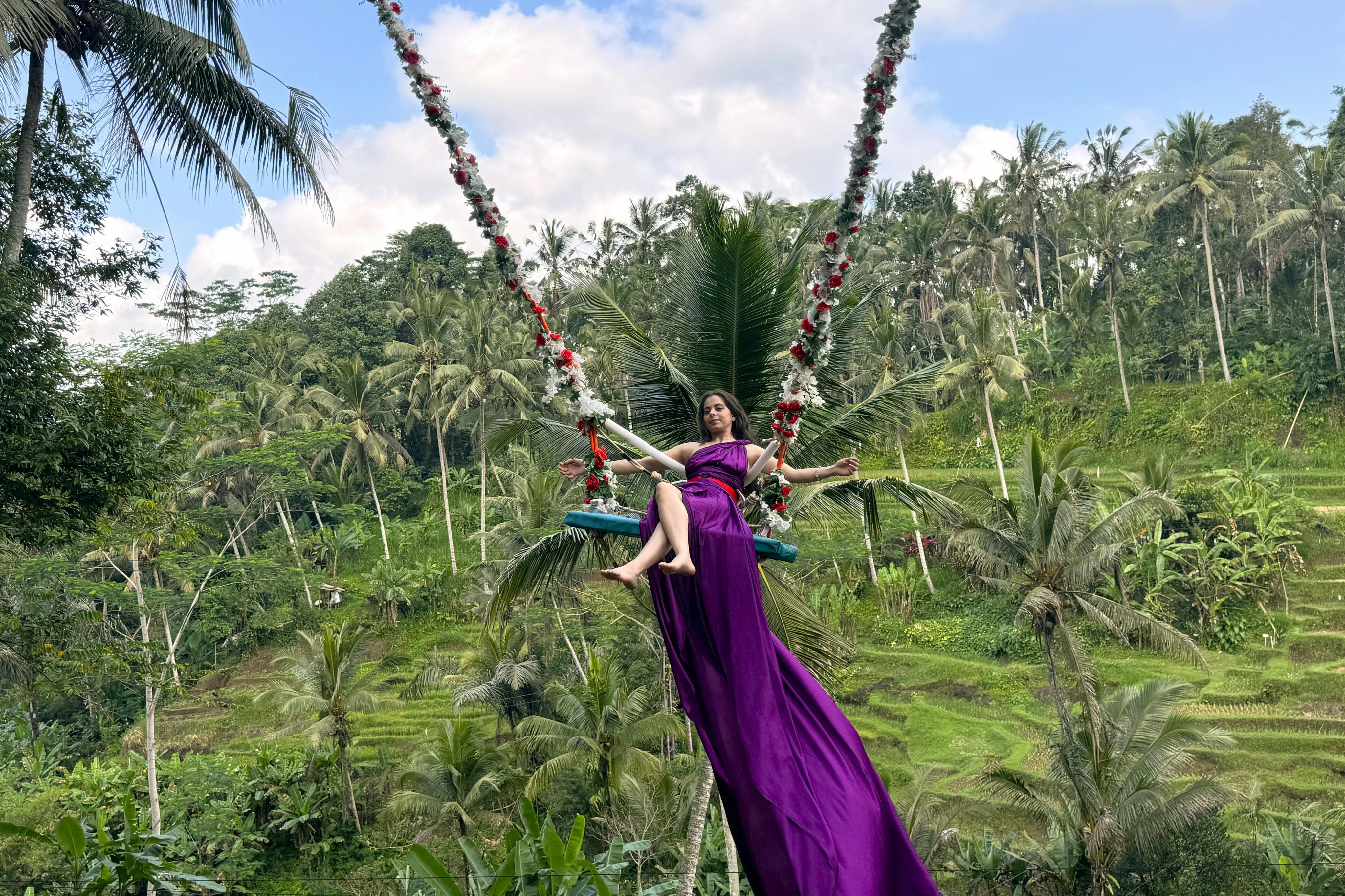 紫色のドレスを着た女性がUファンフィールドでフラワースイングを楽しんでいる