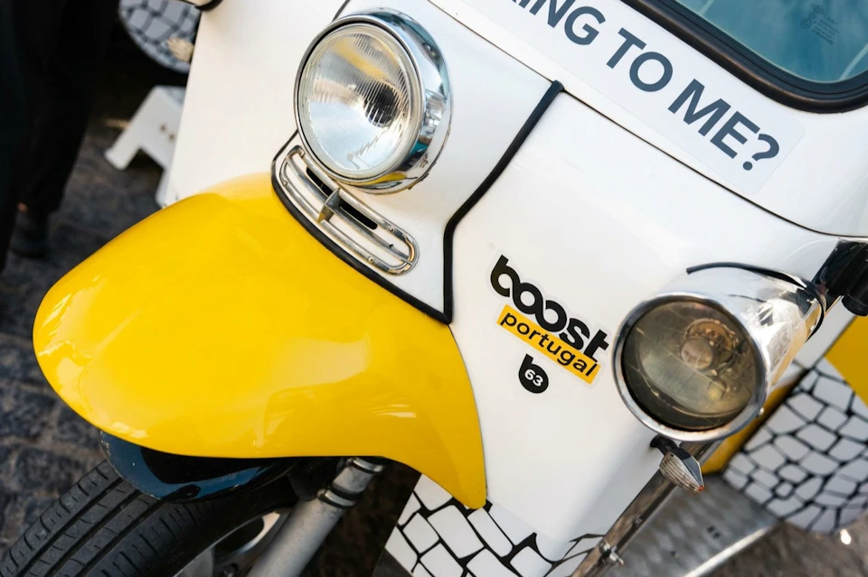 Close-up of a yellow and white tuk-tuk with a "boost Portugal" logo on the front.