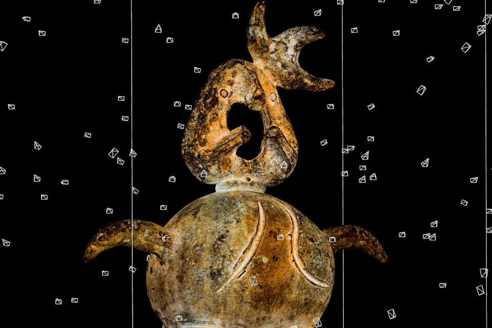 A textured sculpture with an animal-like design and abstract shapes, displayed against a black background.