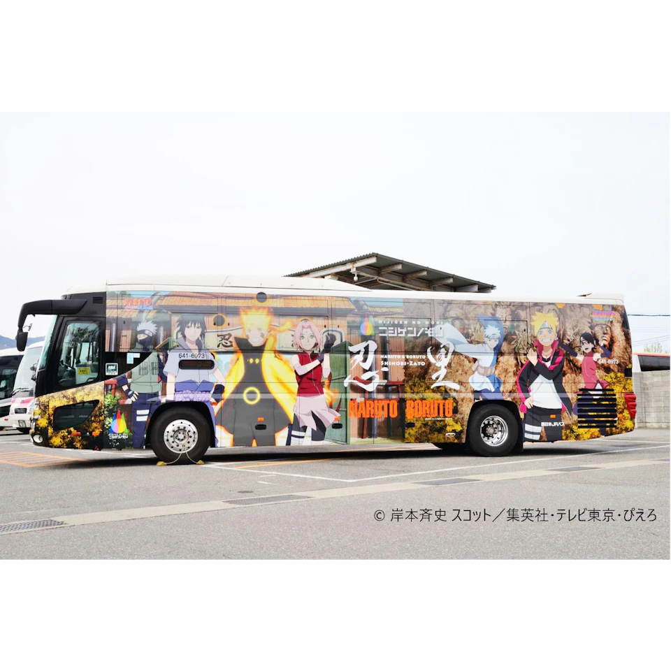 A bus decorated with large, colorful anime characters from the series "Naruto" and "Boruto," parked in a lot near buildings.