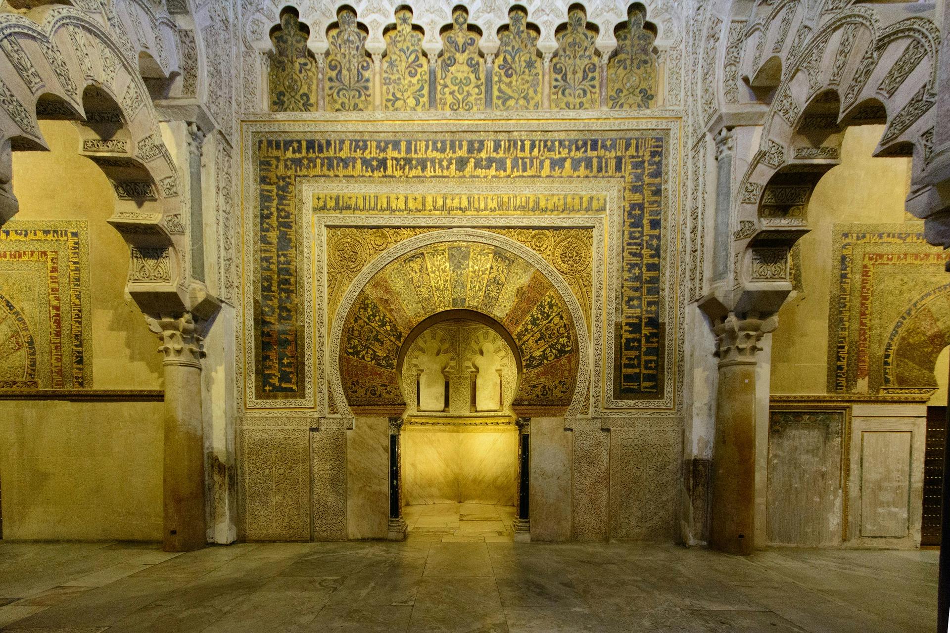 Intricately decorated archway with detailed Islamic geometric and floral patterns, framed by ornate columns in a historic building.