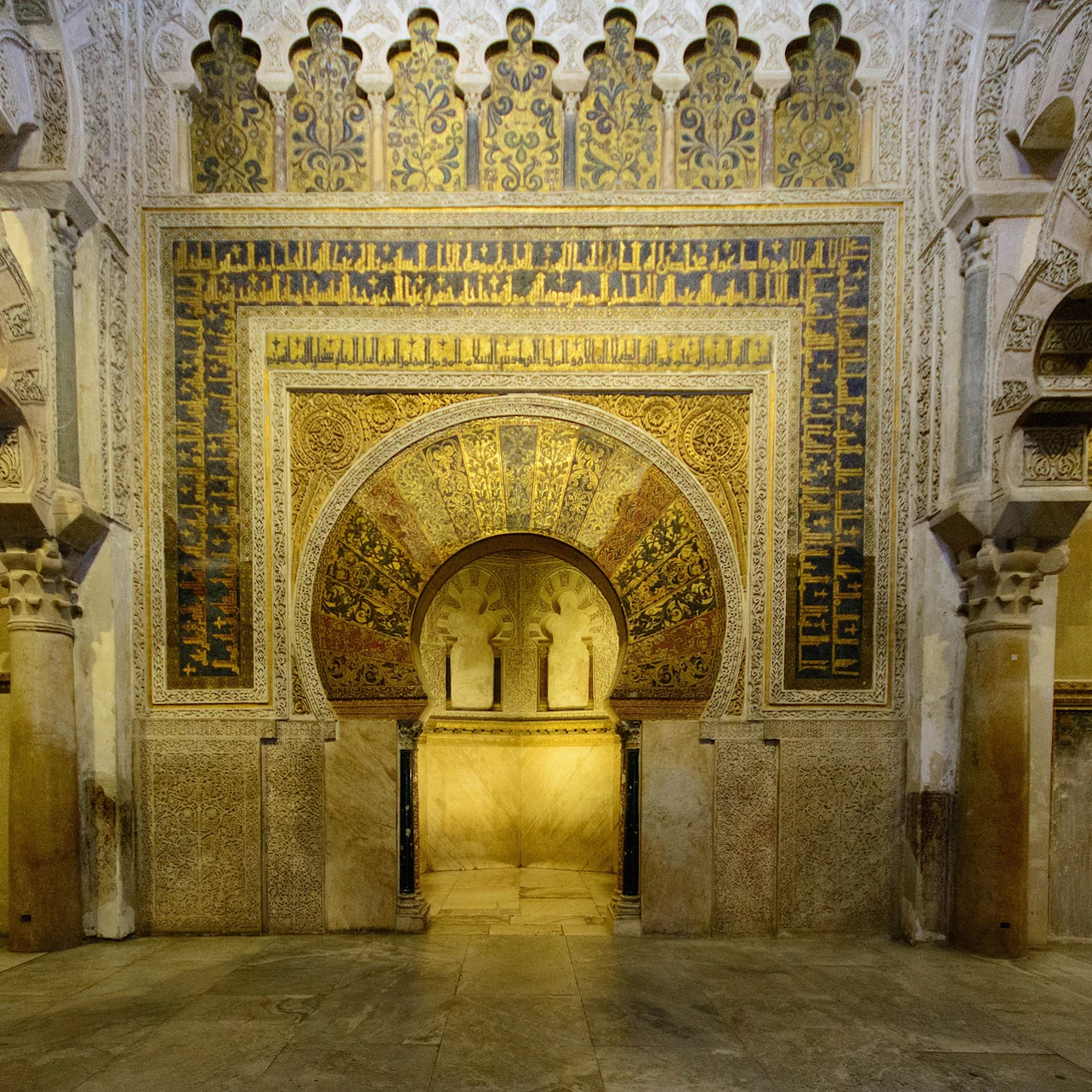Intricately decorated archway with detailed Islamic geometric and floral patterns, framed by ornate columns in a historic building.
