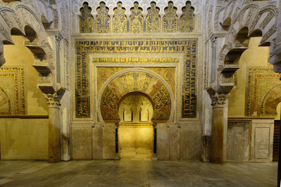 Intricately decorated archway with detailed Islamic geometric and floral patterns, framed by ornate columns in a historic building.