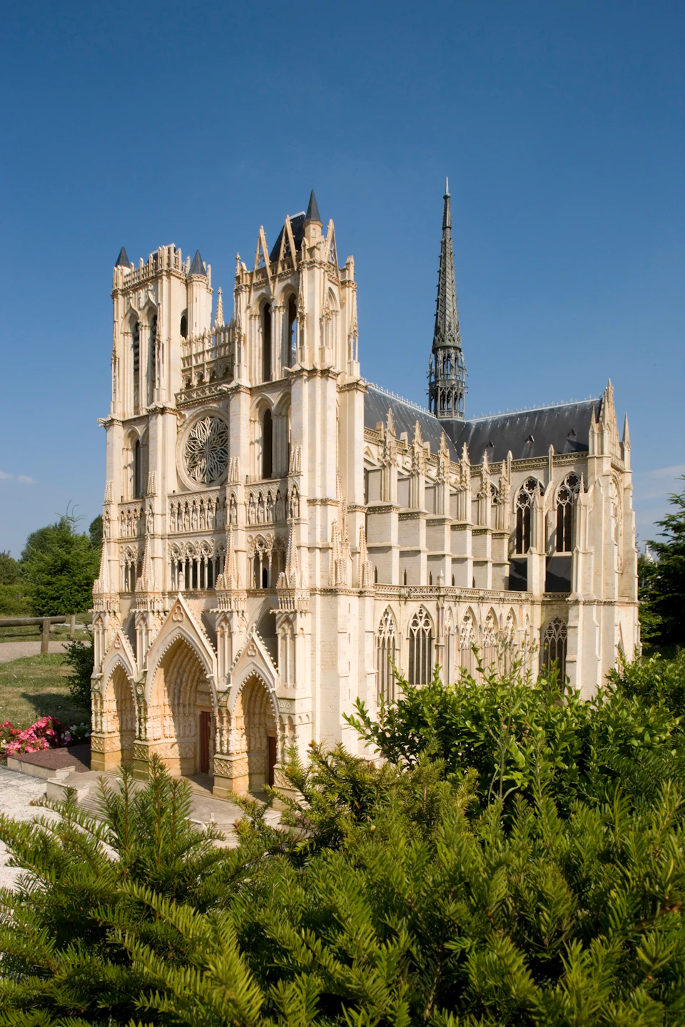 Intricate model of a Gothic cathedral with detailed arches, towers, and spires, set against a clear blue sky.