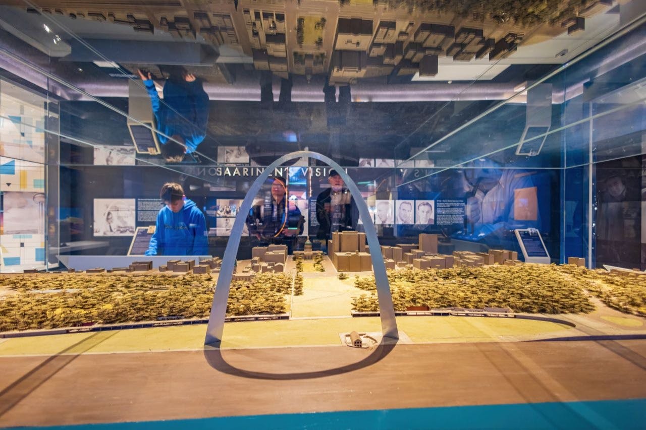 参观者在博物馆展览中观看以门户拱门为特色的城市景观比例模型。