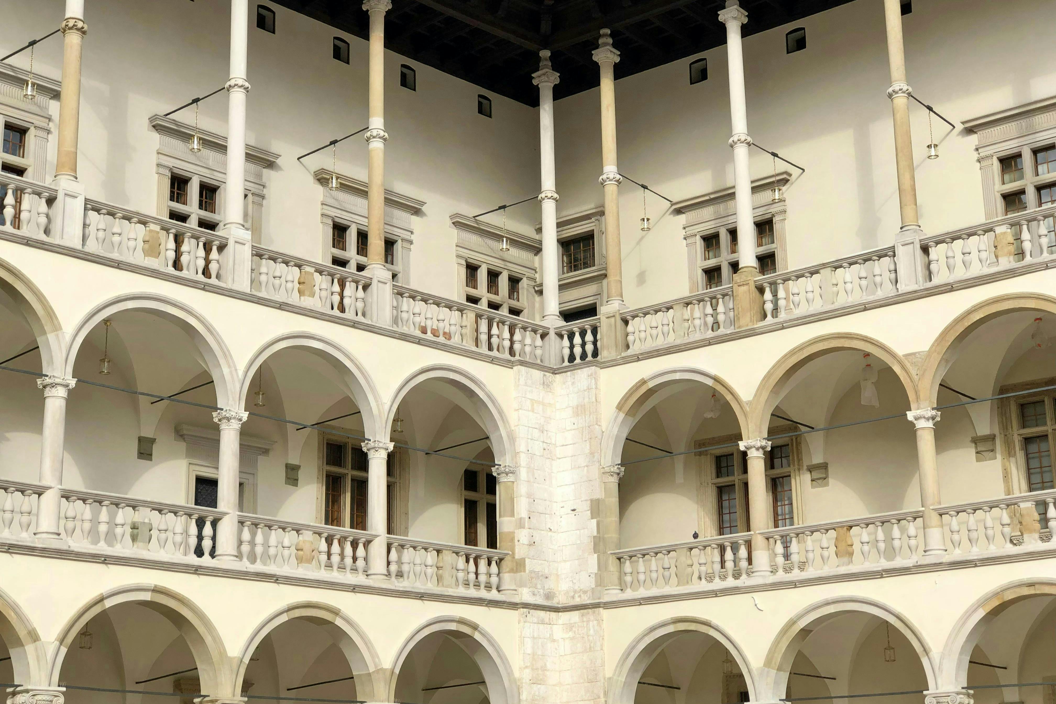 Corner view of a historical building with arches, columns, and balconies, featuring multiple windows.