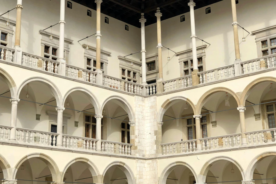 Corner view of a historical building with arches, columns, and balconies, featuring multiple windows.