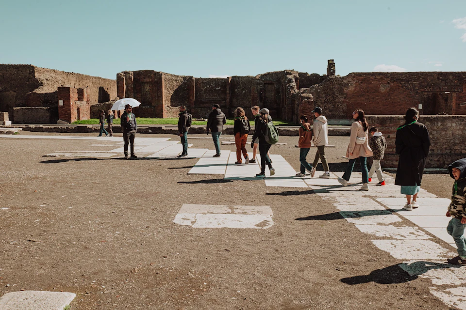 A group of people walking through a historic site with ancient brick ruins under a clear blue sky.