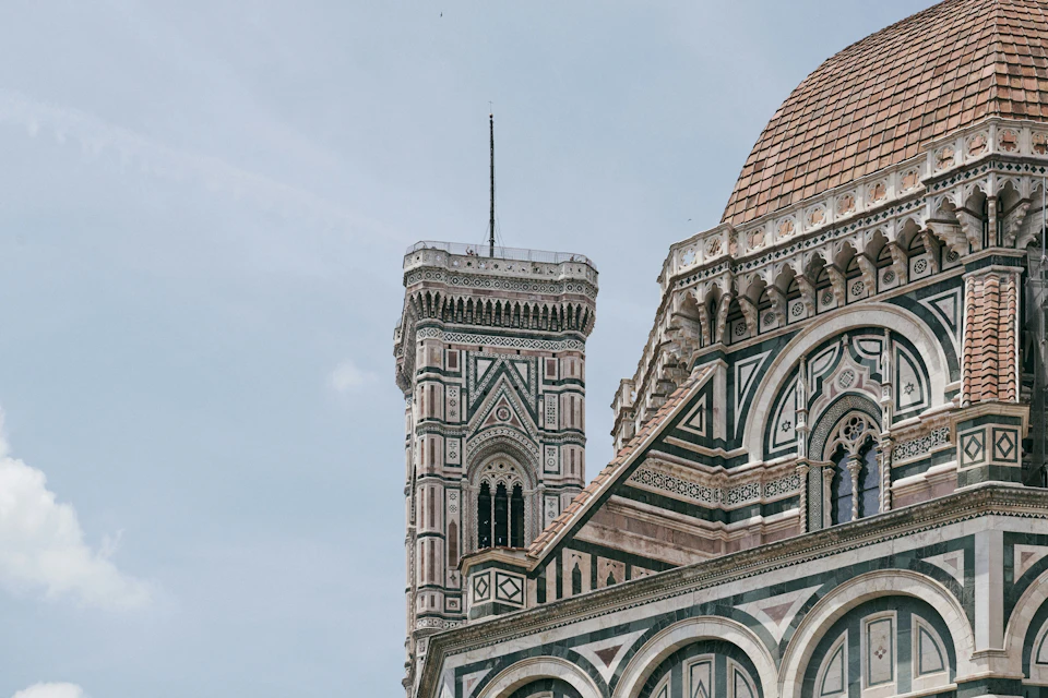 A close-up view of a cathedral with intricate patterns, a tall bell tower, and a domed roof against a blue sky.