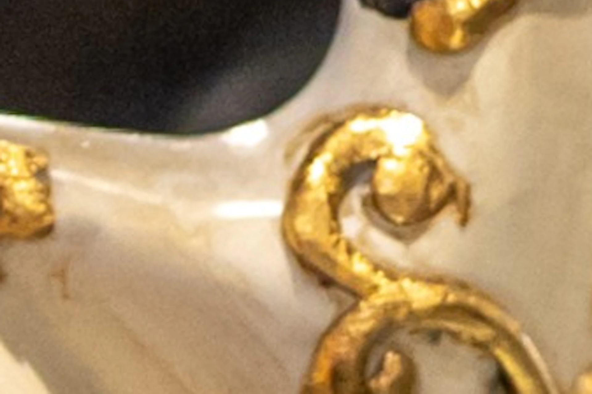 Colorful Venetian-style masks with intricate gold patterns and long noses displayed on a shelf.
