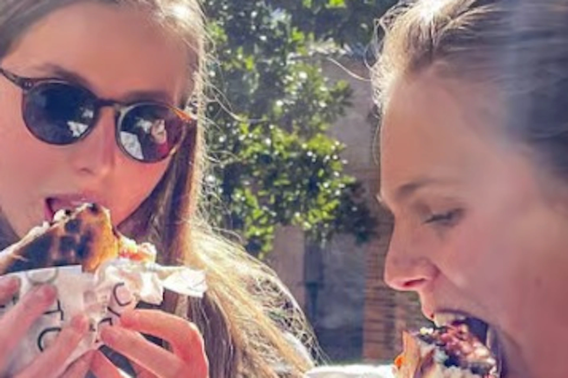 Two women eating sandwiches in the street