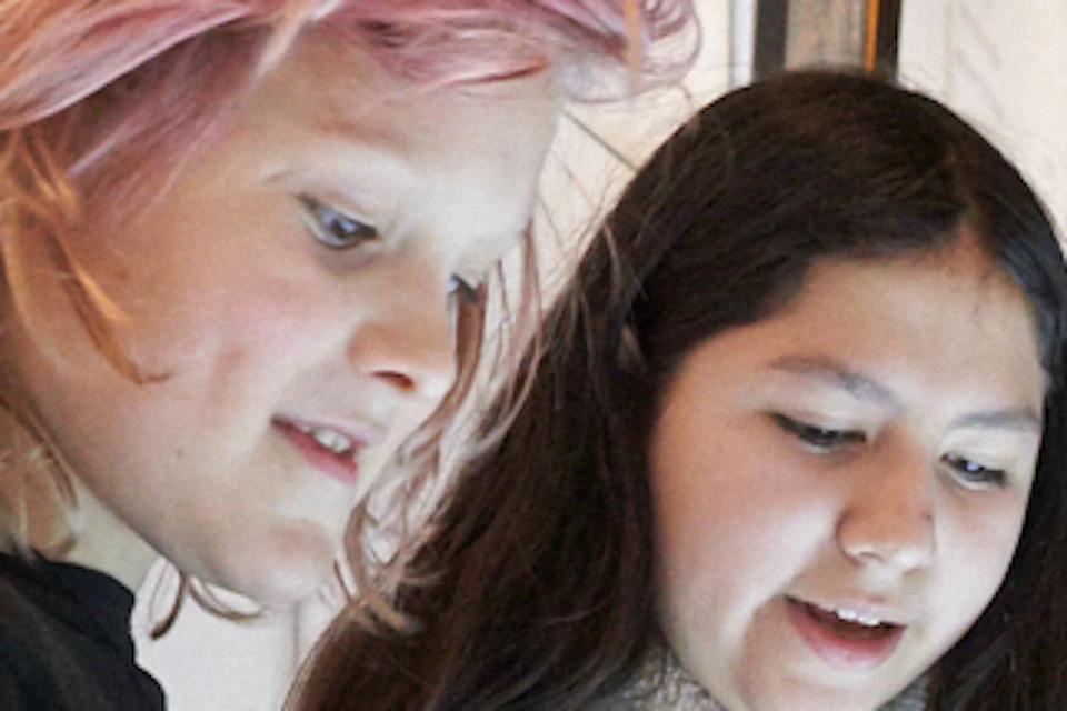 Three children interact with a large touchscreen in a museum, with framed artwork and exhibits visible on the walls behind them.