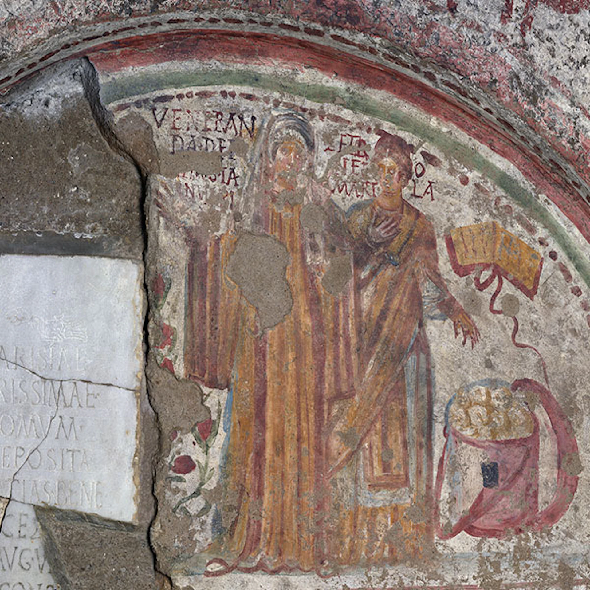 Ancient fresco of two standing figures with faded colors, surrounded by Latin text, visible cracks, and a damaged wall section.