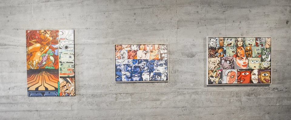 A framed artwork on a concrete wall, featuring a grid of illustrated faces in various expressions, with color sections in blue and orange.