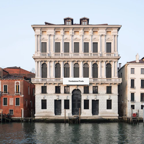 En utsikt över vattnet över byggnader i Venedig, inklusive Fondazione Prada-byggnaden med utsmyckad arkitektur.