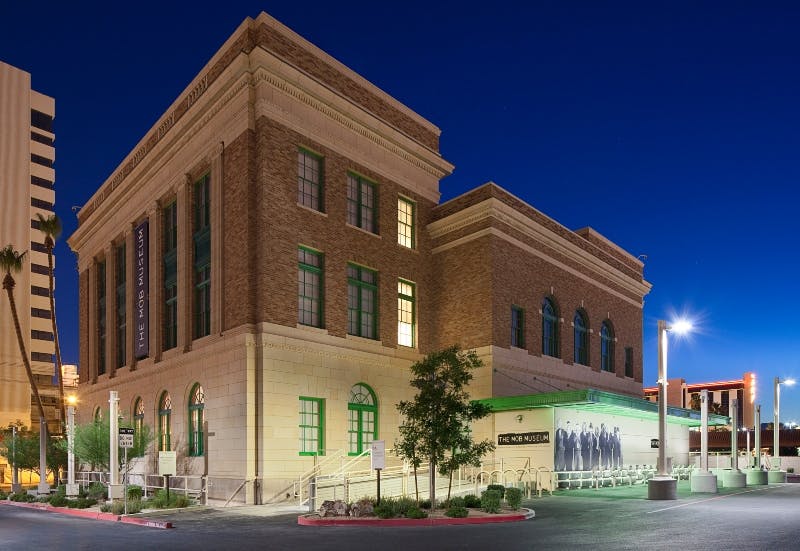 A well-lit, two-story brick building with green-trimmed windows and a sign reading "The Mob Museum" at night.