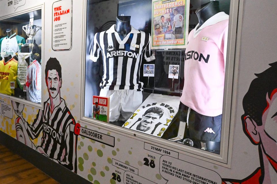 A museum exhibit featuring football memorabilia, including jerseys, trophies, and illustrations on the walls.
