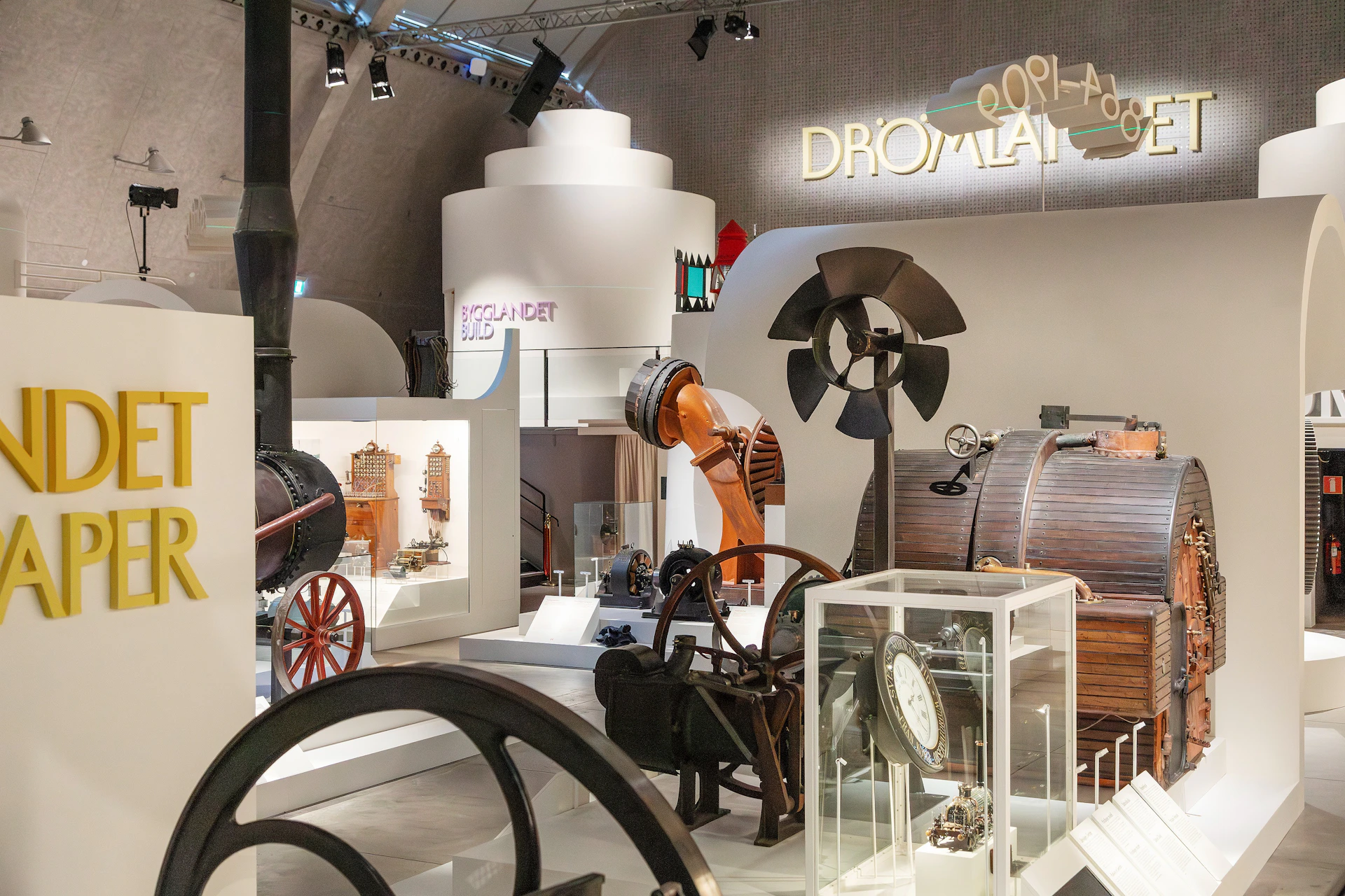 Exhibit of industrial machinery and artifacts in a modern museum, with labeled displays and spotlights.