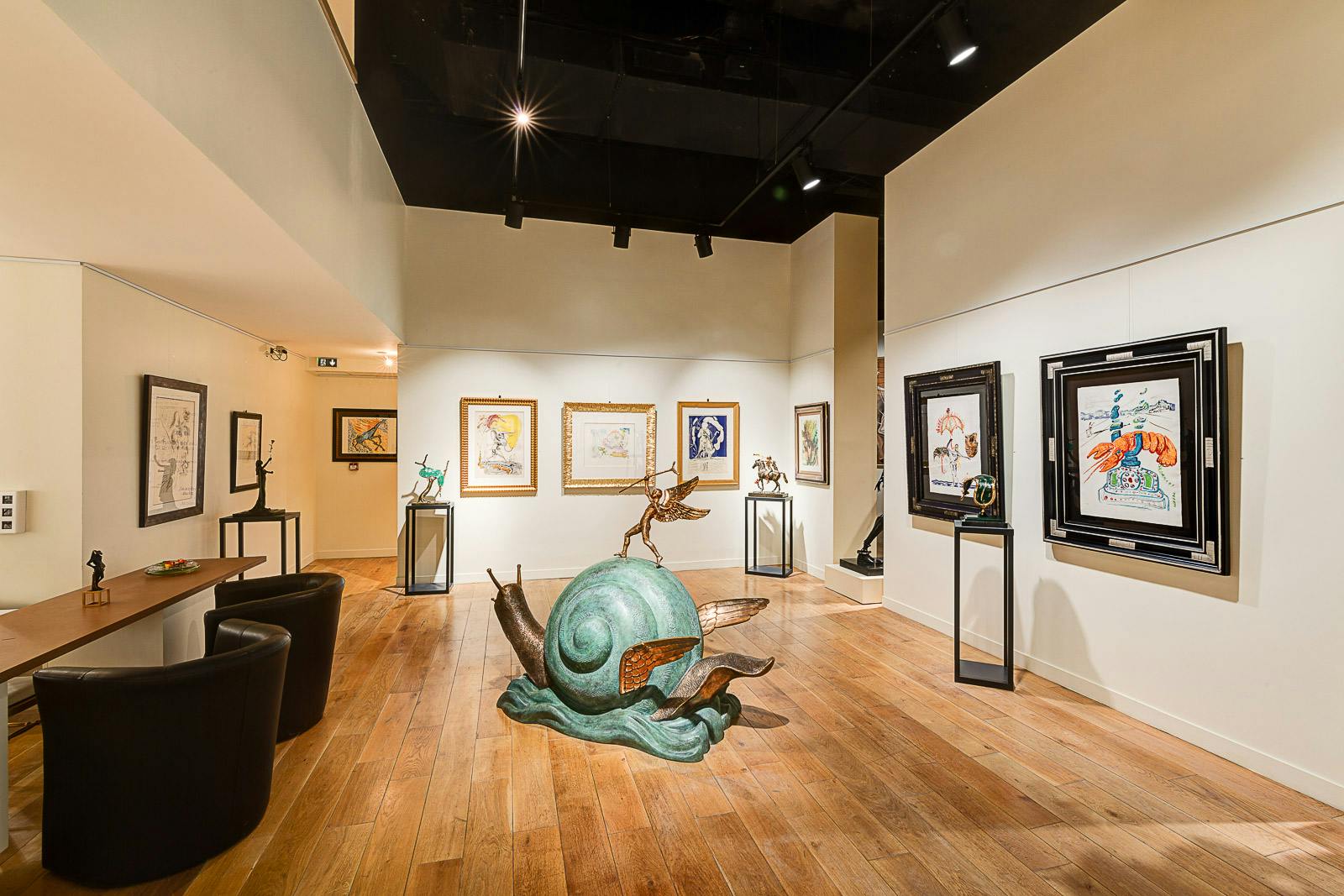 画廊设有带翅膀的大型绿色蜗牛雕塑、墙上的框架艺术品以及展台上的各种雕塑。