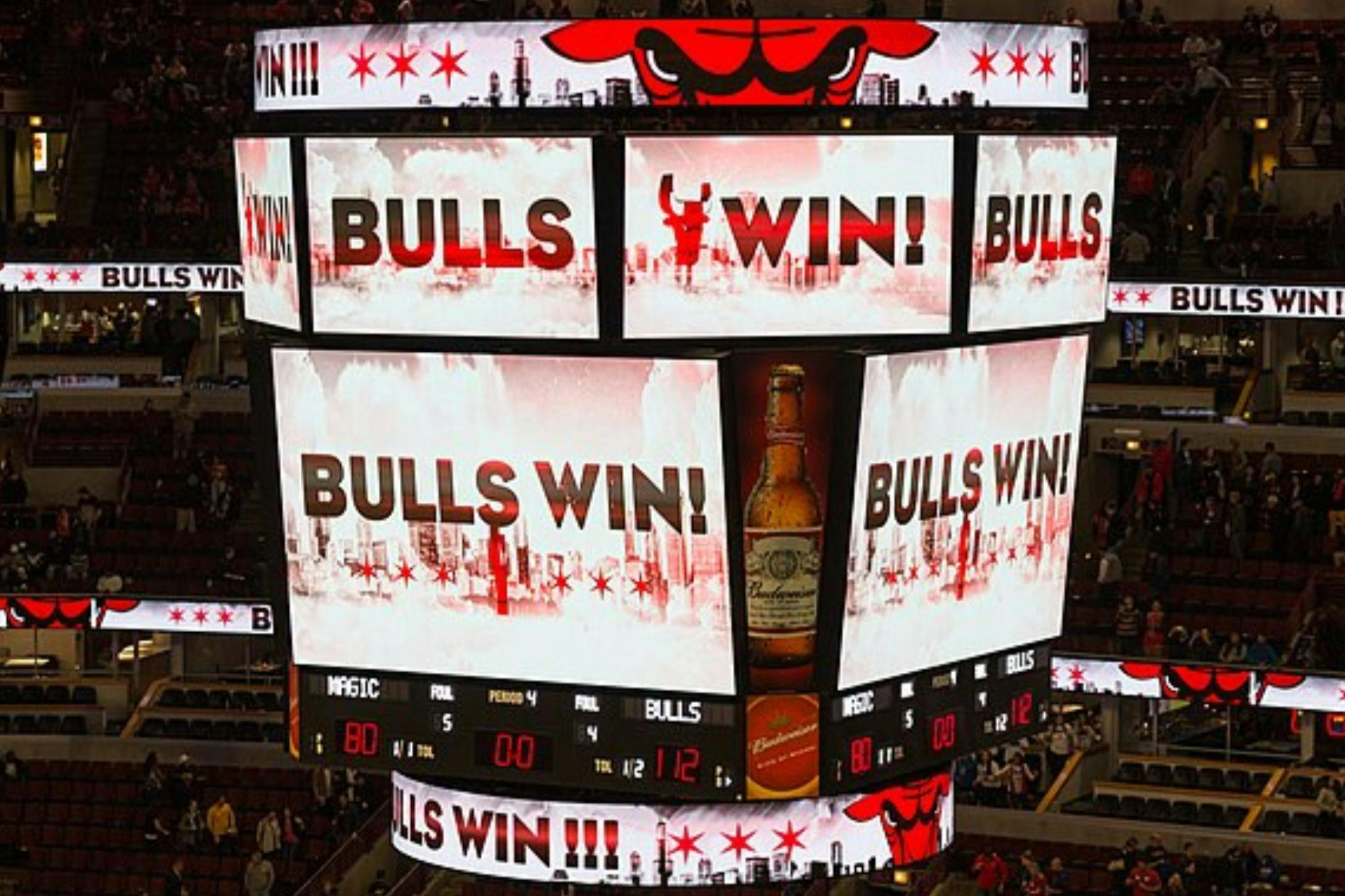 A basketball arena scoreboard displaying "Bulls Win!" prominently, with game scores and decorative graphics.