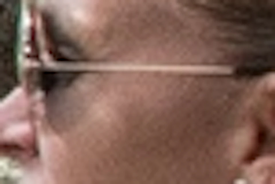 Group of people with bicycles gathered outdoors near a large white house with trees in the background.