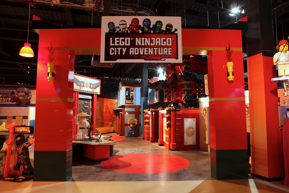 Entrance to LEGO Ninjago City Adventure, featuring large red pillars, LEGO characters, and the game title displayed above.