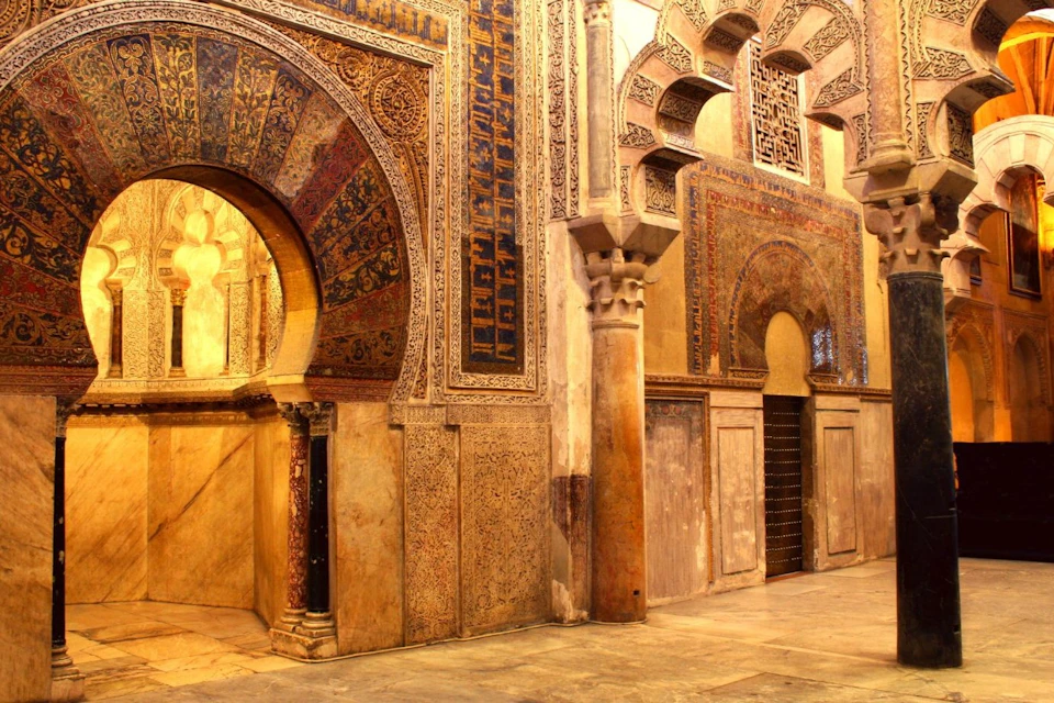 Elaborate Islamic architectural detail featuring ornate arches and intricate geometric and floral patterns on walls.