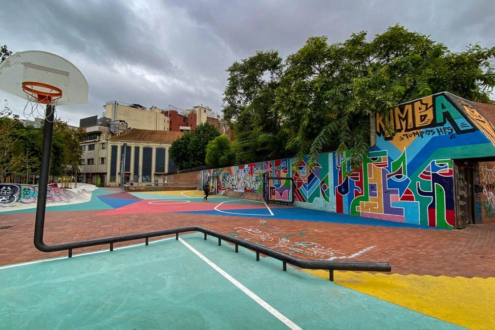 Terrain de jeu avec panier de basket et œuvres d'art de rue sur les murs et le sol.