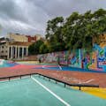 Parc infantil amb cèrcol de bàsquet amb obres d'art de carrer a les parets i al terra.