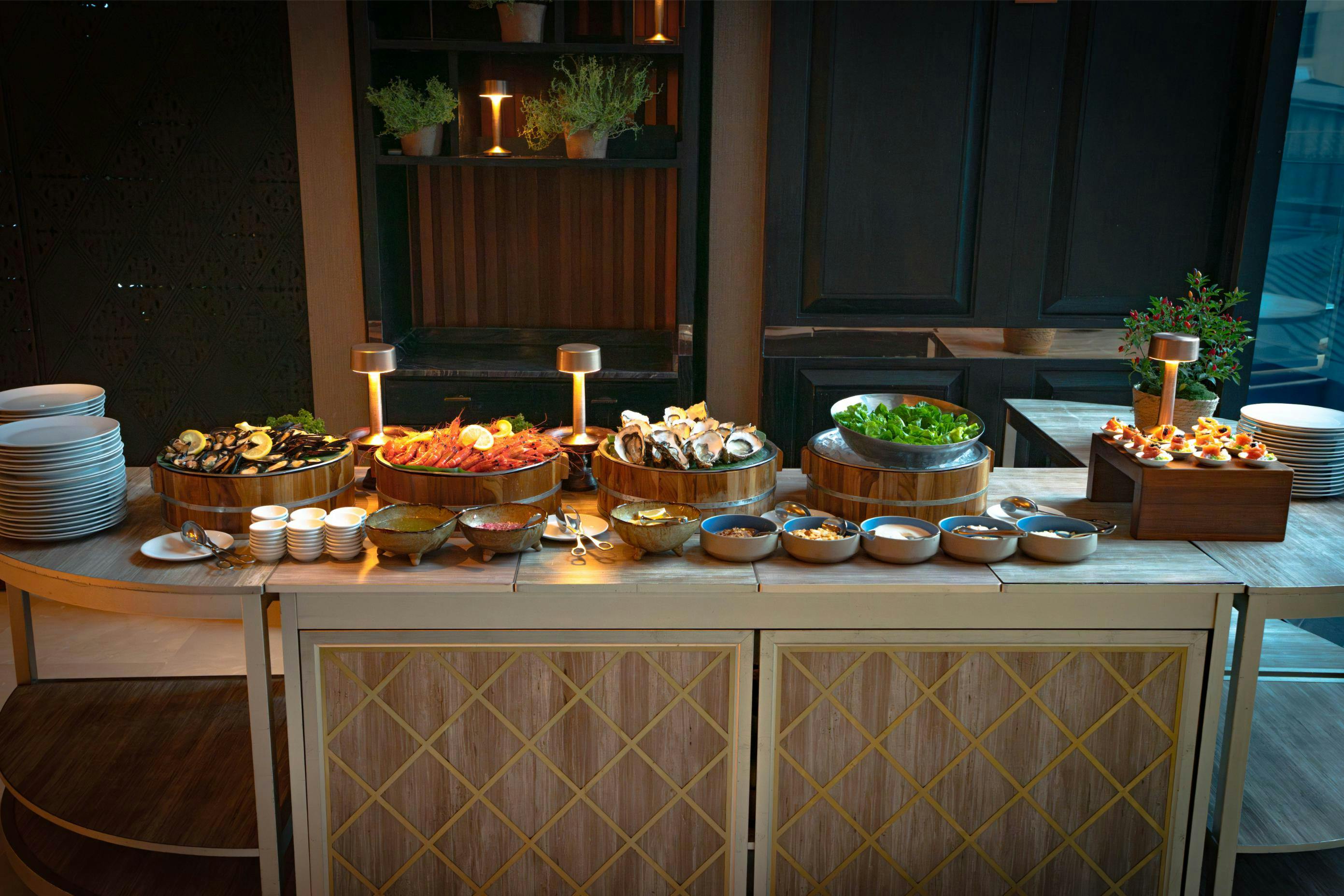 A buffet table with various dishes, including salads, sushi, and appetizers, in a restaurant setting with warm lighting.