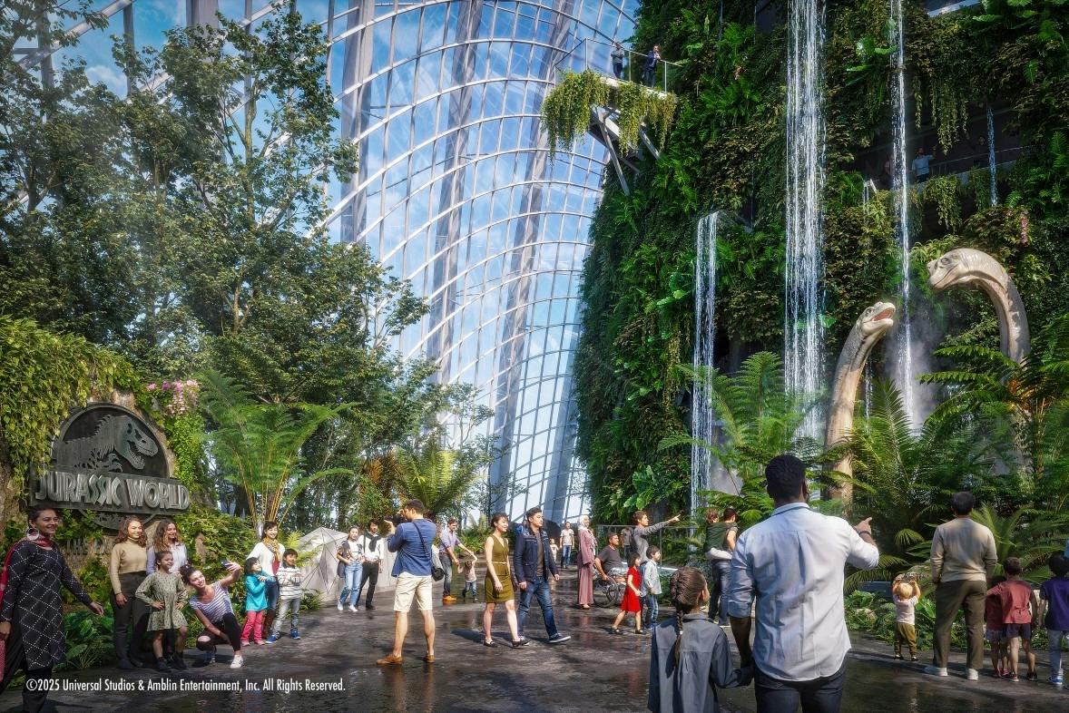 A group of people walking and interacting in a lush indoor garden with a glass ceiling and a "Jurassic World" sign.