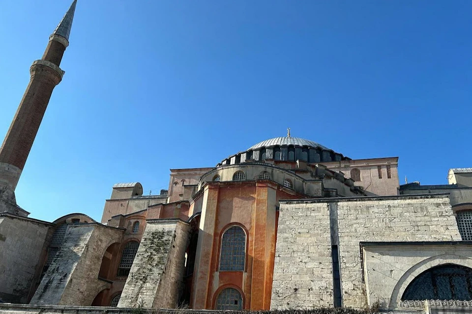 A historic building with a large dome and multiple arched windows, set against a clear blue sky.