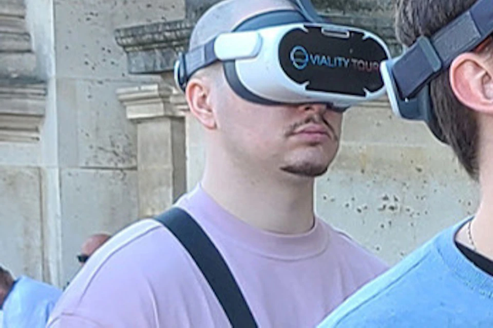 A group of people wearing VR headsets standing outdoors near a classical building with stone columns.