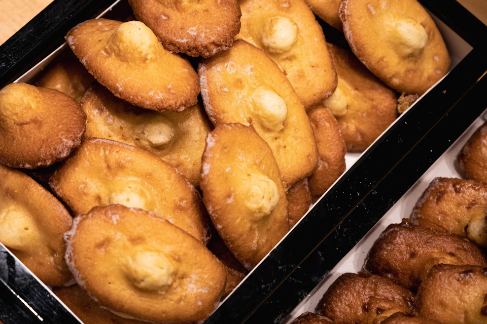 A tray of golden-brown pastries, each with a dollop of cream or filling in the centre, arranged closely together.