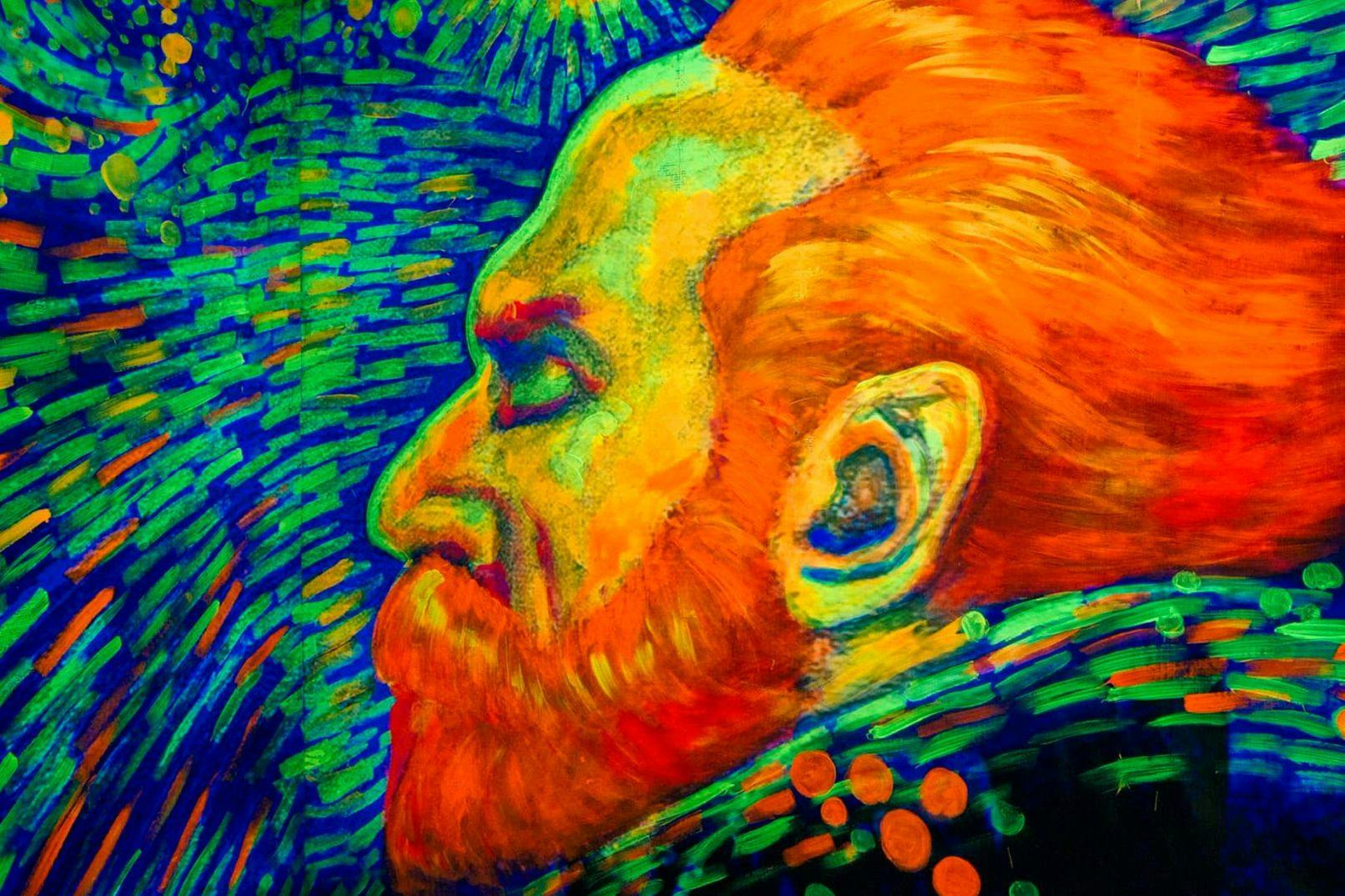 A vibrant, abstract painting of a man's profile with orange hair and beard, featuring bold blue and green background strokes.