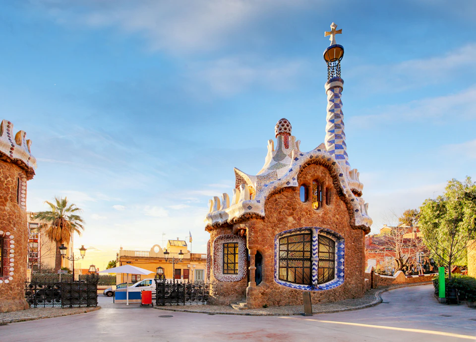 A unique, colorful building with a twisted tower and intricate details under a clear sky, likely in Park Güell, Barcelona.