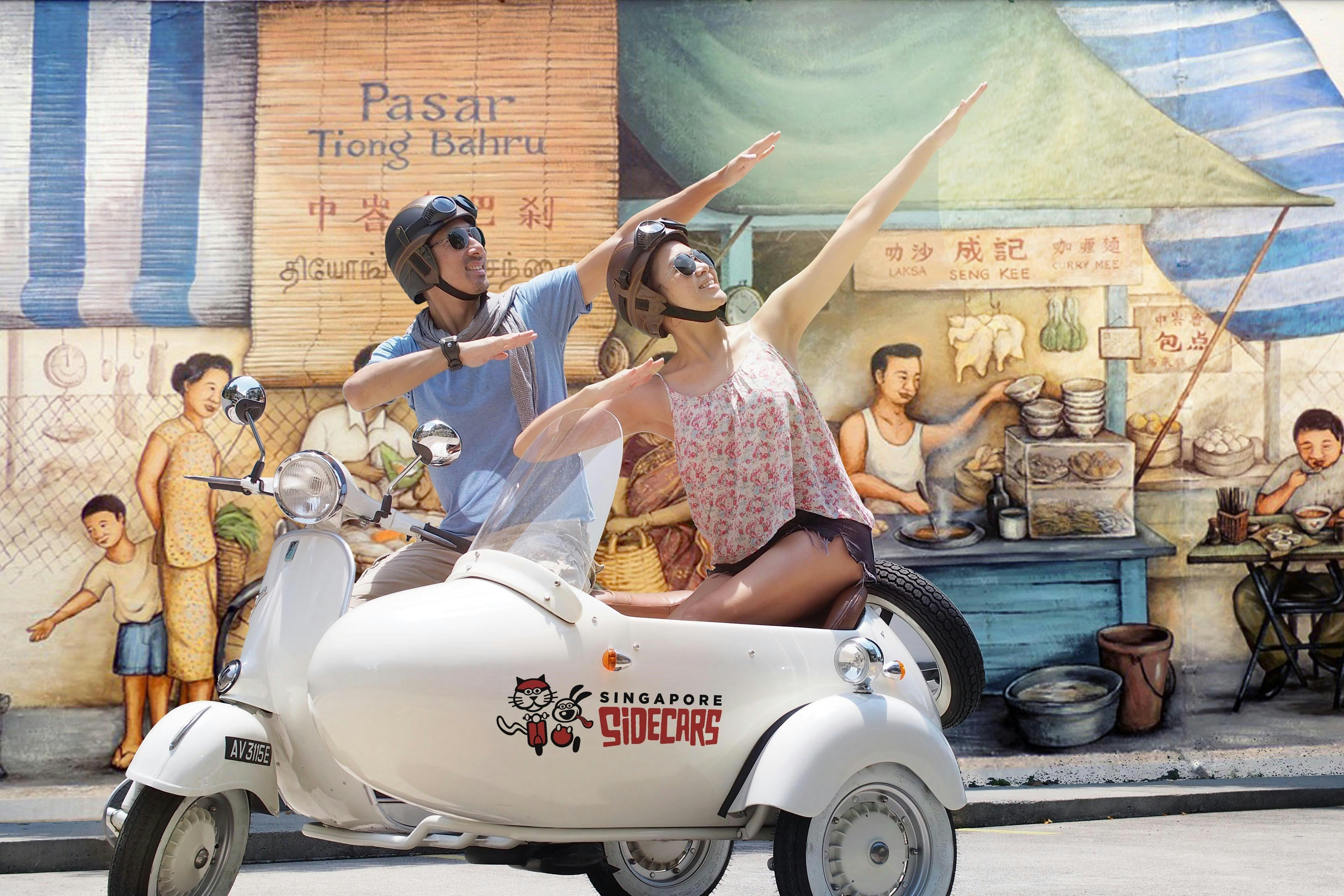 Deux personnes casquées posent sur un side-car blanc, imitant la peinture murale derrière eux d'un stand de nourriture de rue animé.